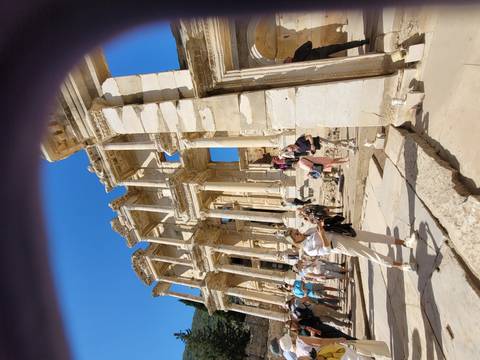 Tourists exploring ancient ruins with tall columns.