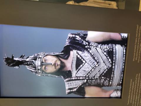       Blurred display of a figure in costume, possibly for a historical exhibit.
  