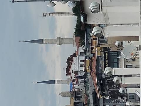       Urban rooftop view with minaret spires and satellite dishes.
  