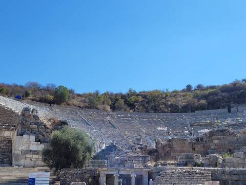       Ancient amphitheater ruins with tourists around.
  