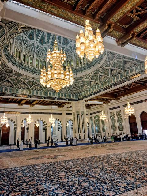 Interior of a grand mosque with chandeliers and intricate architecture.