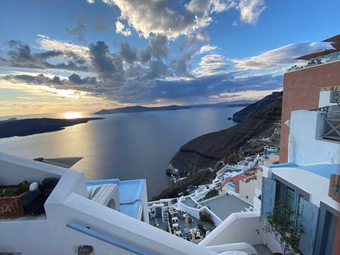       A stunning view of a cliffside town overlooking the sea at sunset.
  