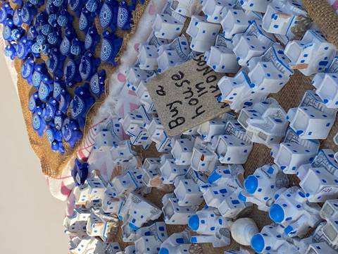       Souvenir miniatures of Cycladic houses and blue evil eye charms on a table.
  