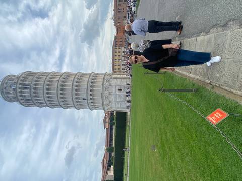 Tourist posing in front of the Leaning Tower of Pisa.