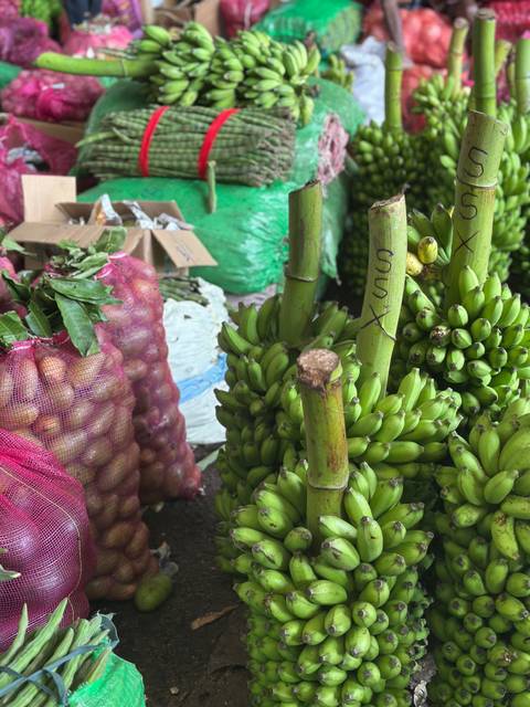 Market scene with bunches of bananas and vegetables.