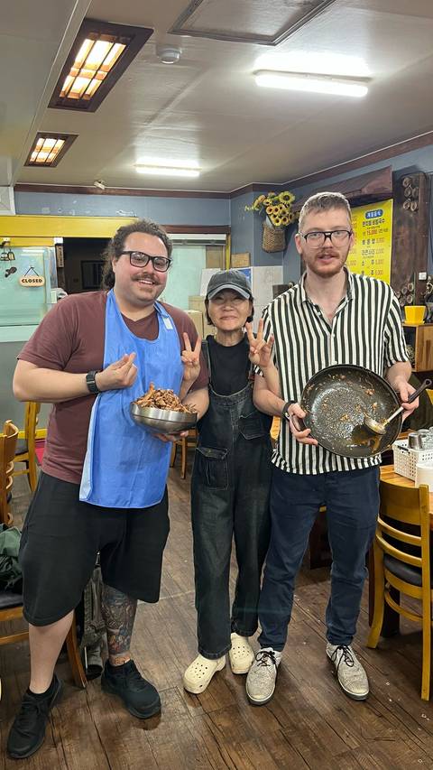 Three people posing with food in a restaurant.