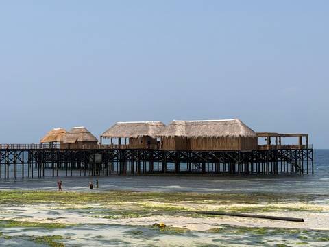       Thatched structures on stilts over the ocean.
  