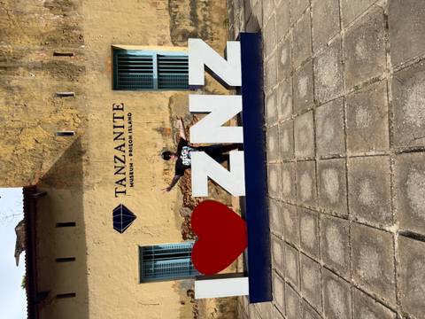 Person posing by Zanzibar landmark sign.
