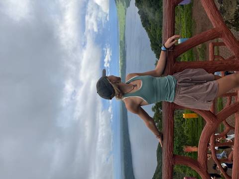       Person standing on a wooden terrace overlooking a lake.
  