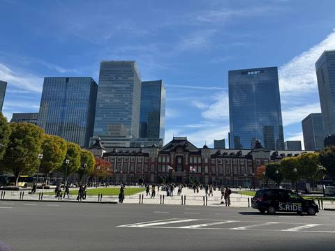 Tokyo Station with surrounding skyscrapers under a clear blue sky.
