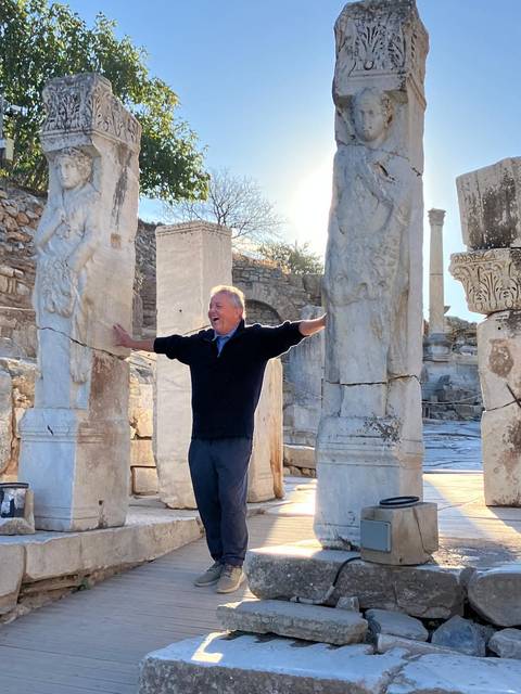 A man posing joyfully among ancient stone ruins.
