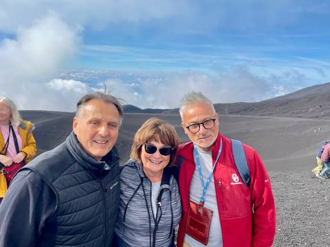      Three people on a mountainous landscape with clouds
  