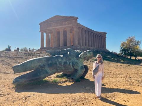 Person posing in front of a historic temple and fallen statue