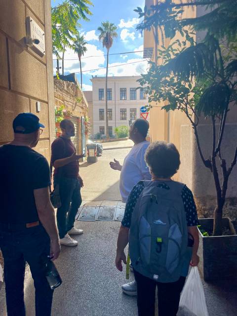       Group of people conversing in a sunlit alley
  