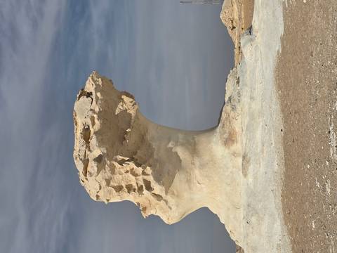 White rock formation against a cloudy sky.