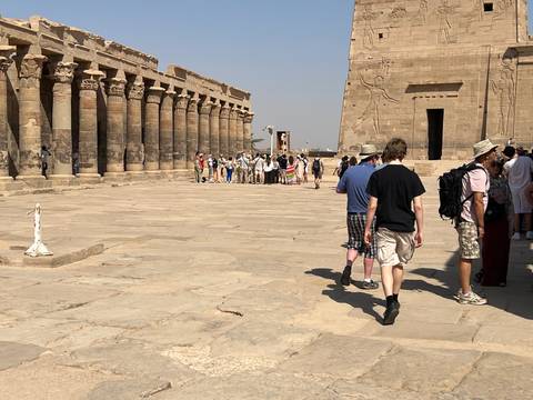       Tourists walking around an ancient Egyptian temple with columns.
  