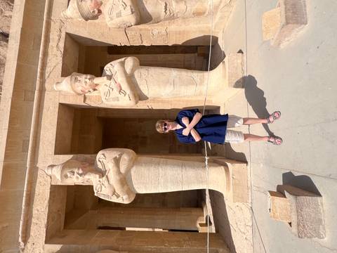 A person standing between two ancient statues at a temple.