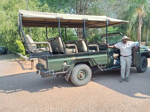       A safari vehicle parked with a driver leaning against it.
  