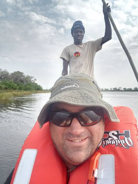       A person wearing a hat and life vest on a boat.
  