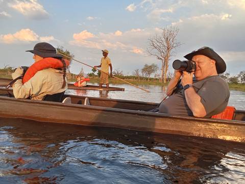       People taking photos from a canoe during a river trip.
  