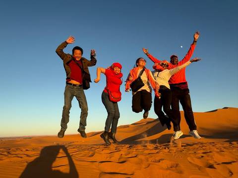 Group of people jumping with joy in a desert landscape.