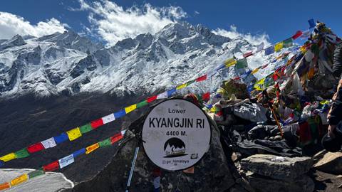       High-altitude mountainous landscape with colorful prayer flags.
  