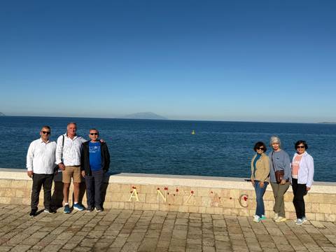 Group of people standing near a sea view with a historical reference to ANZAC.