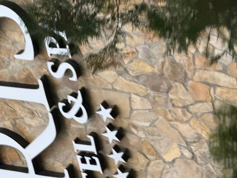 Close-up of a sign with unreadable text and a blurred stone background.