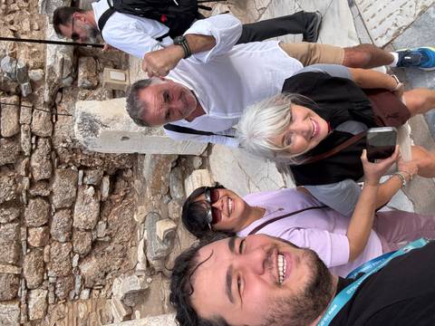 Group of people posing in front of ancient stone ruins.