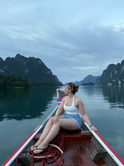 Person in a boat admiring the tranquil lake and mountain scenery.