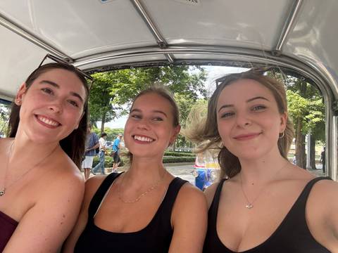 Three people smiling inside a vehicle.