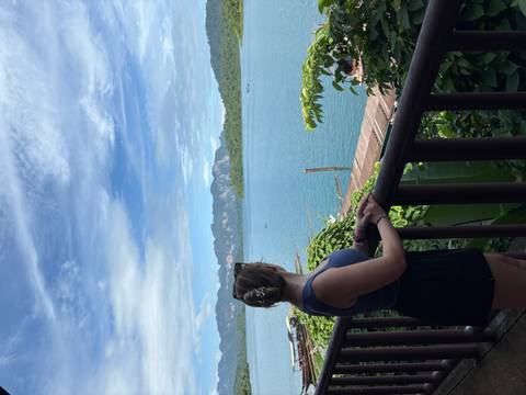 Person overlooking a scenic lake with mountains in the distance.