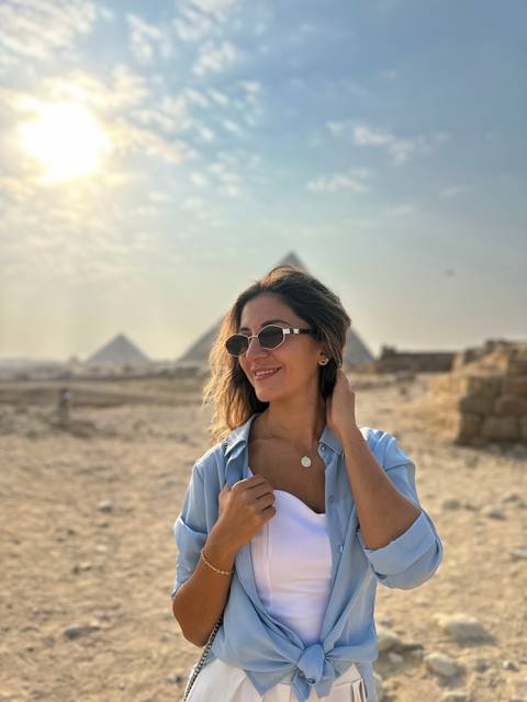 Person wearing sunglasses with pyramids in the background.