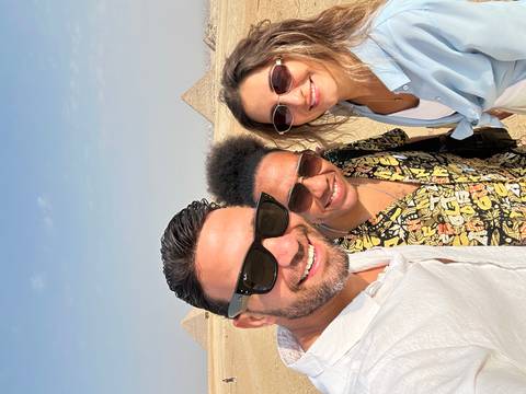 Three people taking a selfie with pyramids in the background.