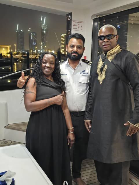       Three people standing together, posing onboard.
  