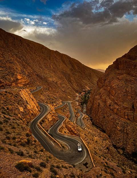 Winding mountain road through rugged terrain at dusk.