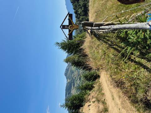 Scenic countryside with a wooden cross and mountain view.