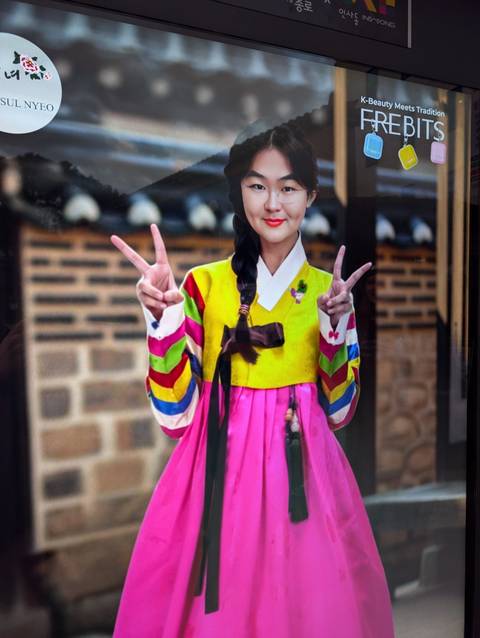 Person in traditional attire posing with peace signs.