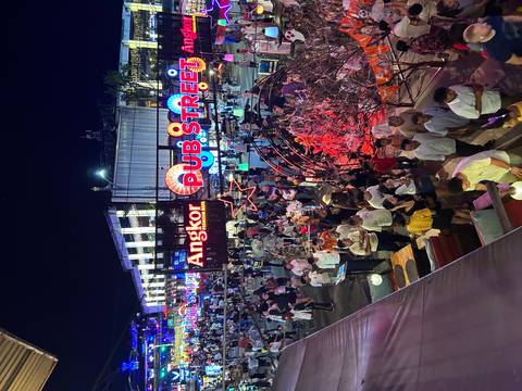       Night scene of a busy street illuminated with colorful lights and lots of people.
  