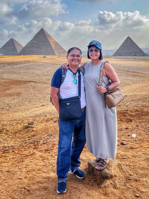 Couple posing together on a landscape with a desert backdrop.