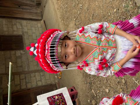       Child in traditional attire with colorful headpiece.
  