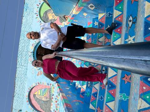 Two people standing on colorful painted stairs looking at the camera.