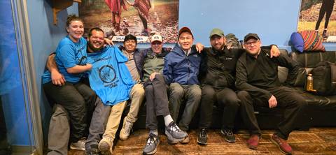      Group of friends sitting together in a cozy room with prominent wall decor.
  