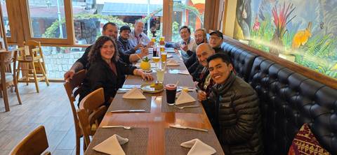       A group enjoying a meal together at a large dining table in a restaurant.
  