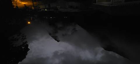      Mountains covered with clouds at night, lit by street lights.
  