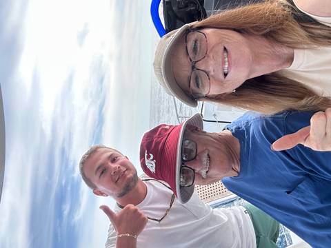       Three people taking a selfie on a boat with the sea in the background.
  