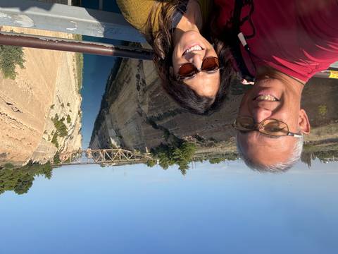       Couple posing in front of a canal and distant bridge.
  