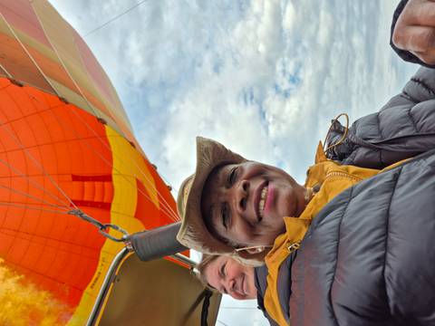 Woman taking a selfie in a hot air balloon with a large smile.