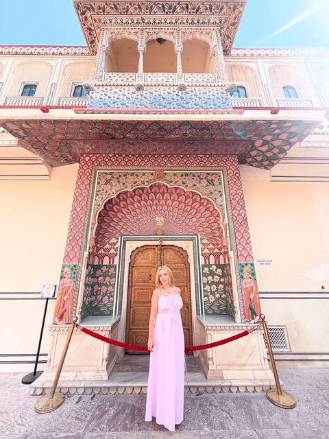 A woman standing in front of a colorful door at the Jaipur City Palace.