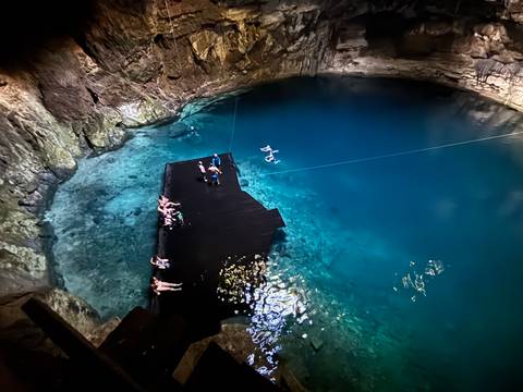 A beautiful cenote with crystal clear water and a wooden platform.